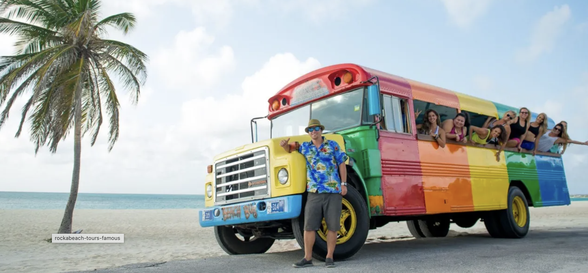 Colorful RockaBeach Tours bus on the beach in Aruba